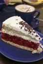 Slice of cherry layer cake with cream and a cup of cappuccino Royalty Free Stock Photo