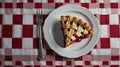Slice of Cherry Pie with Lattice Crust on White Plate and Red Checkered Tablecloth Royalty Free Stock Photo