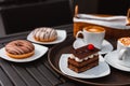 Slice of chocolate cake, Cutlery steak basket and donot with coffee on the table