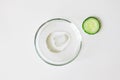 Slice of cucumber and transparent cosmetic gel smudge in glass petri dish on white background. Making natural organic cosmetics Royalty Free Stock Photo