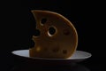 Slice of curd cheese laying on plate looking like half moon in backlight. Close up. Studio shot