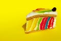 A Slice Of Delicious Colored Cake On Yellow Background. Rainbow Cake.