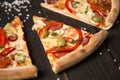 Slice of delicious pizza with vegetables and meat on dark board. Sea salt on background Royalty Free Stock Photo