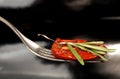 Slice of dried tomato on fork on black background