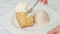 Slice of fresh baked apple cake with biscuit base and sliced apples and whipped cream topping served with vanilla ice cream close Royalty Free Stock Photo