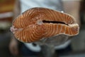 A slice of fresh carcass of red fish in the hand of the seller in the store. Close-up. Healthy food and diet