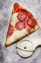 Slice of fresh Italian classic original Pepperoni Pizza and pizza cutter on grease stains white cardboard. Royalty Free Stock Photo