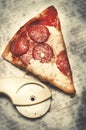 Slice of fresh Italian classic original Pepperoni Pizza and pizza cutter on grease stains white cardboard. Royalty Free Stock Photo