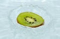 Slice of fresh kiwi falling into water Royalty Free Stock Photo