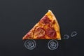 Slice of fresh pepperoni pizza with vehicle wheels drawn on chalkboard, food delivery concept, creative idea