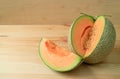 Slice of fresh ripe muskmelon sliced from the whole fruit isolated on a wooden table