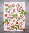 Slice of fresh rye bread with cream cheese with red fish, cherry tomatoes and salami parsley on a striped tablecloth on w Royalty Free Stock Photo