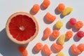 Slice of grapefruit and sweet fruit hard candies on white table background. Overhead view of colorful caramel mix.