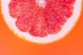 Slice of half red grapefruit on orange background, juicy citrus section texture. Abstract summer wallpaper, bright tropical Royalty Free Stock Photo