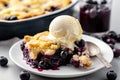 Slice of home baked delicious blueberry crumble with a scoop of vanilla ice cream on a plate with juicy jammy berry filling Royalty Free Stock Photo