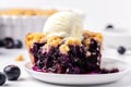 Slice of home baked delicious blueberry crumble with a scoop of vanilla ice cream on a plate with juicy jammy berry filling on Royalty Free Stock Photo