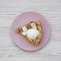 Slice of homemade apple pie with ice cream on pink plate over white wooden surface, top view. Flat lay, overhead, from above Royalty Free Stock Photo