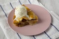 Slice of homemade apple pie with vanilla ice cream on a pink plate, side view Royalty Free Stock Photo