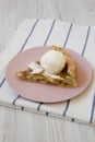 Slice of homemade apple pie with vanilla ice cream on a pink plate, side view. Close-up Royalty Free Stock Photo