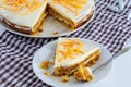 A slice of homemade carrot cake with cream and a white and brown checkered towel on a white kitchen table. Vegan and Gluten Free Royalty Free Stock Photo