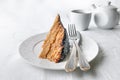 A slice of homemade multilayer biscuit cake. Soaked in butter. Served with chocolate icing and coconut. On a white plate is a fork Royalty Free Stock Photo