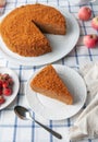 A slice of homemade multilayer honey cake. Orange color. On a white plate. View from above. Testura. Nearby are berries, apples,