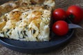 A slice of homemade Turkish pastry borek on a gray plate and some cherry tomatoes