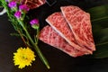 Slice Japanese beef neck chuck or jyu rosu wagyu serving on black plate and decorate with flower. Preparation for BBQ