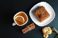 Slice of layered honey cake Medovik decorated with anise star on white plate, sticks of cinnamon, a cup of tea with lemon, dried r Royalty Free Stock Photo