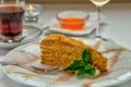 Slice of layered honey cake. A rosette with honey, a glass of cool white wine and a cup of thick aromatic tea. Selective focus