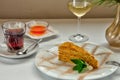 Slice of layered honey cake. A rosette with honey, a glass of cool white wine and a cup of thick aromatic tea. Selective focus