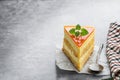 Slice of layered mango cheesecake on gray background