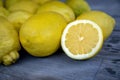 Close up of Slice of lemon along with a group of lemons on a wood table