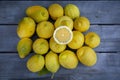 Slice of lemon along with a group of lemons on a wood table