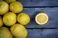 Slice of lemon along with a group of lemons on a wood table