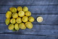Slice of lemon along side a group of lemons on a wood table