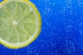 Slice of lemon in the blue water with bubbles Royalty Free Stock Photo