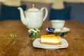 Slice of lemon cheesecake with cup of tea with flowers. Royalty Free Stock Photo