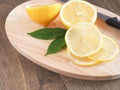 Slice lemon fruit with leaves and knife on cutting board. Royalty Free Stock Photo