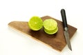 Slice lemon or lime in a wood board and a knife, in a white background.