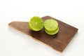 Slice lemon or lime in a wood board, in a white background.