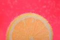 Slice of lemon in sparkling water on pink background, closeup. Citrus soda Royalty Free Stock Photo