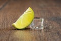 Slice of lime and a melting ice cube with drops of water on the table. Royalty Free Stock Photo