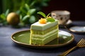 Slice of matcha biscuit cake with pistachio and vanilla layers on grey background. Sweet food concept. Pistachio dessert close up