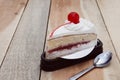 Slice of milk cake with cherry put on wood texture