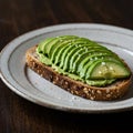 A slice of multigrain bread is topped with neatly arranged avocado slices. The bright Royalty Free Stock Photo