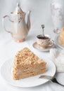 Slice of multilayer Napoleon cake with butter cream. On a white plate. Close-up. Next to a plate is a napkin and a fork. In the Royalty Free Stock Photo