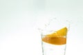 Slice the orange slice in a glass of water and make a spray on a white background. water spray in the air. a slice of citrus drops Royalty Free Stock Photo