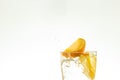 Slice the orange slice in a glass of water and make a spray on a white background. water spray in the air. a slice of citrus drops Royalty Free Stock Photo