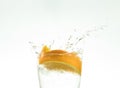 Slice the orange slice in a glass of water and make a spray on a white background. water spray in the air. a slice of citrus drops Royalty Free Stock Photo